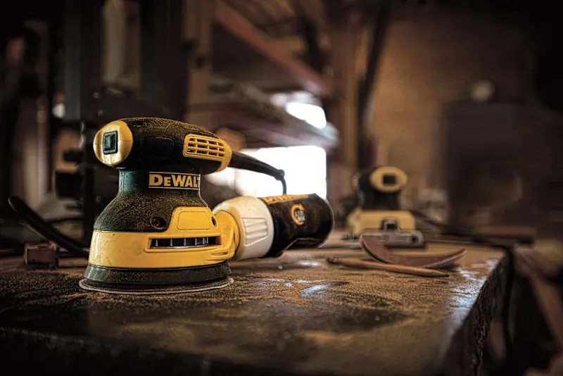 Photo of DEWALT sander on workbench, SKUs DWE6421-AR, DWE6421-B3, DWE6421-B2, DWE6421-BR, DWE6421, workshop setting.